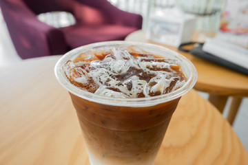 cold late coffee in takeaway cup on wooden table at coffee shop