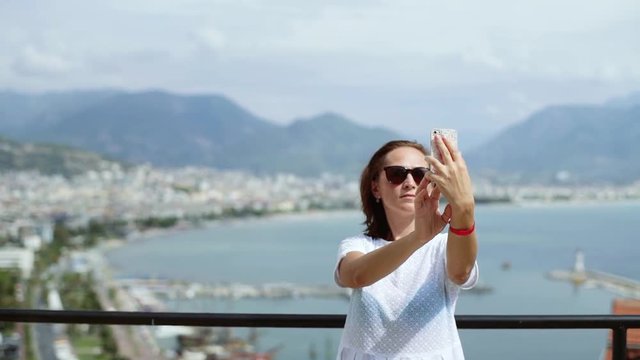 Woman in sunglasses makes selfie on the background of the city. Travel to different cities.