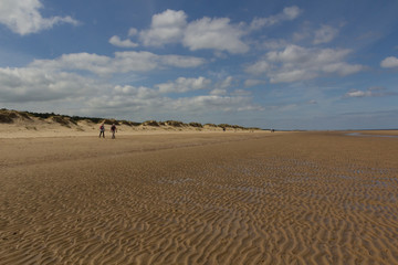 Fototapeta na wymiar Sand dunes and people walking on the beach at Wells-next-the-Sea