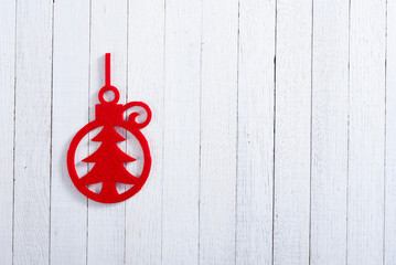 red felt Christmas ornament on white wooden table background