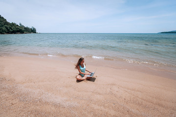Fototapeta na wymiar Young happy fitness yoga woman working with her laptop sitting in the beach in Thailand , relaxing enjoy with nature