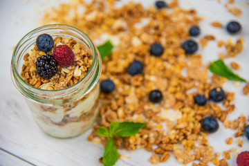 Jar full with granola, yogurt and fresh berries, close-up, selective focus, top view.