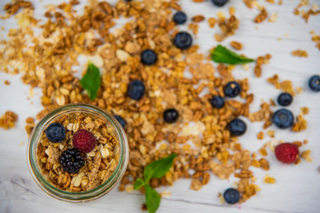 Jar full with granola, yogurt and fresh berries, close-up, selective focus, top view.