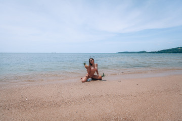 A beautiful girl holding the pineapple and having fun on the beach