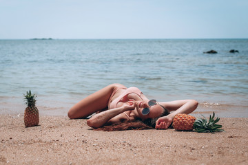 Beautiful woman in swimsuit relaxing on a beach WITH PINEAPPLE