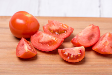 Juicy red tomato chopped on a wooden board on a white background