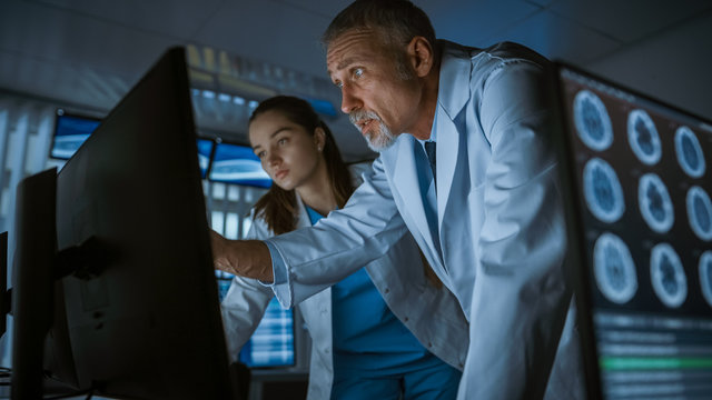 Two Medical Scientists / Neurologists, Talking and  Working on a Personal Computer in Modern Laboratory. Research Scientists Making New Discoveries in the fields of Neurophysiology, Science
