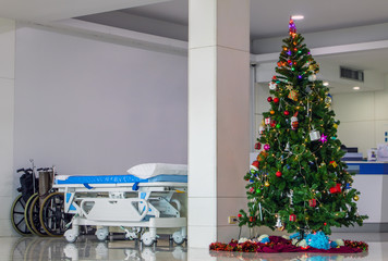 A empty wheelchair and wheel bed for patient with Christmas tree at hallway of hospital. Christmas...