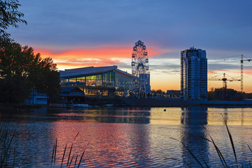 Obraz premium ferris wheel at sunset with cloudy sky on river