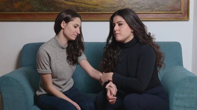 fraternal love. a woman consoling her depressed sister on sofa