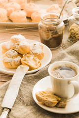 Espresso in a white coffee cup served with homemade profiteroles on a wooden table.