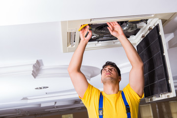 Fototapeta na wymiar Repairman repairing ceiling air conditioning unit
