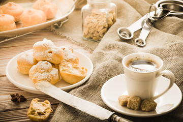 Espresso in a white coffee cup served with homemade profiteroles on a wooden table.