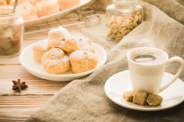 Cup of hot black coffee with home made profiteroles on a rustic wooden table.