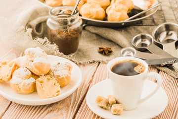 Espresso in a white coffee cup served with homemade profiteroles on a wooden table.