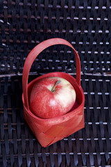 Ripe aromatic apples on the background of a wicker basket of vines.