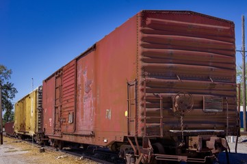 Obraz premium Stare zardzewiałe czerwone i żółte stalowe wagony kolejowe w słoneczny dzień