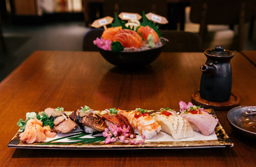Many kinds of Japanese Sushi on ceramic plate on wood table in restaurant
