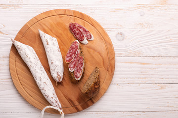 Salami and bread on white wooden background. Top view. Copy space