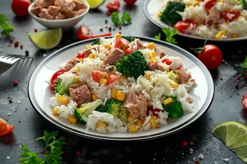 Photo sur Plexiglas Plats de repas Salade de riz au thon frais avec maïs sucré, tomates cerises, brocoli, persil et citron vert dans un bol noir