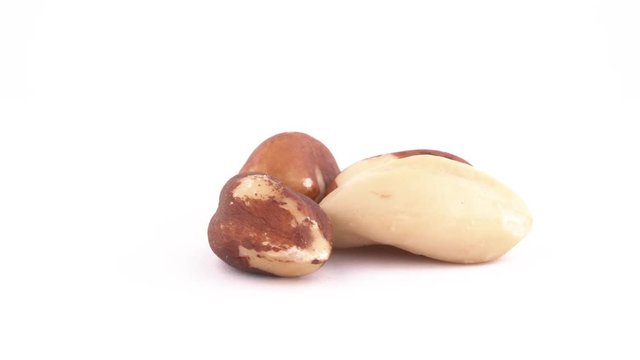 Four blanched brazil nut. Slowly rotating on the turntable isolated on the white background. Close up. Macro.