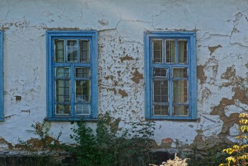 two blue retro windows on the gray wall of the old house
