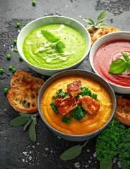 Variety of cream soup bowls: sweet pea and mint, tomato and basil and butternut squash with steamed kale and fried halluomi