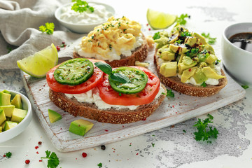 Fototapeta na wymiar Vegetarian Healthy bread toasts with cottage cheese, heirloom tomatoes, scrambled eggs and avocado