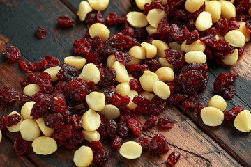 Healthy snack of Dried cranberries and macadamia nuts in a ceramic bowl on rustic wooden table