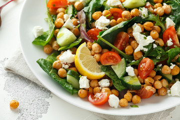 Chickpeas Salad with cucumber, tomatoes, feta cheese and green mix in a white plate. healthy food.