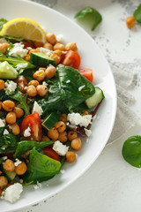 Chickpeas Salad with cucumber, tomatoes, feta cheese and green mix in a white plate. healthy food.