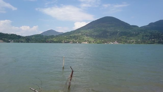Aerial Establishing shot of Lake / reservoir through barbe wire with mountain in background