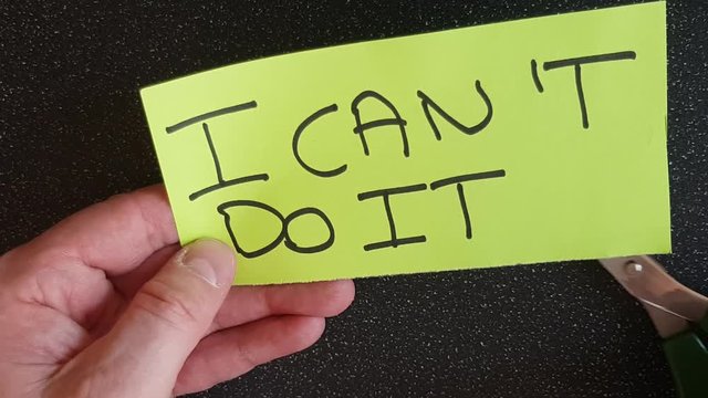 Man using scissors to remove the t from the word can't t leaving the positive motivational part. I can do it.