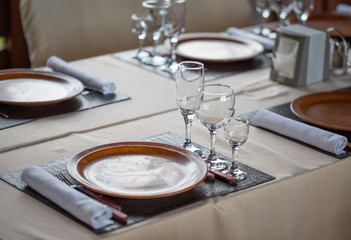 Glasses, forks, knives, plates on a table in restaurant served for dinner