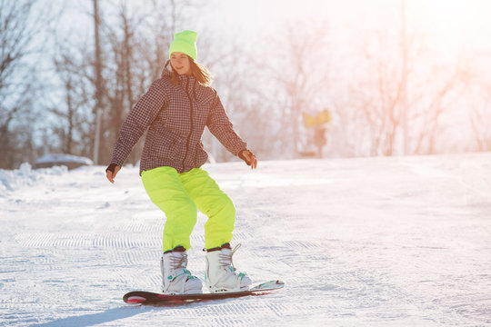 Winter sport activity, woman snowboarder riding on slope