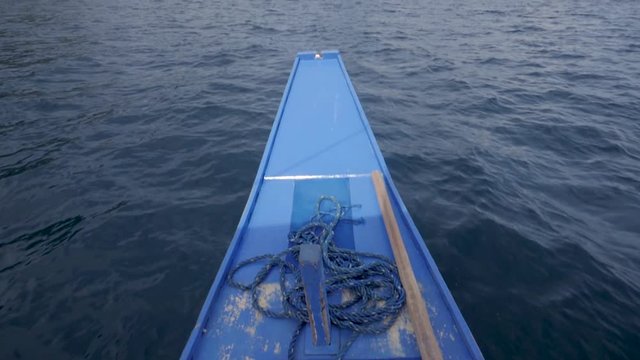 Ultra slow motion shot of front of traditional filipino bangka boat sailing on blue waters towards beautiful limestone cliffs in the Philippines. Camera tilting up