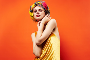 Naklejka premium bright fashionable woman in a headdress a yellow dress on a red background