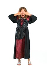 A full-length shot of a Kid dressed as a vampire at halloween holidays covering eyes by hands isolated on white