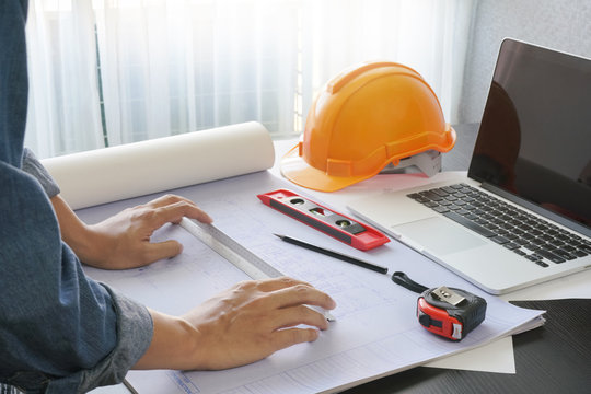 architect working on table with blueprint and construction tools - business and industrial concept