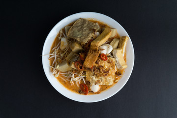 Curry noodles in a plate on dark background with selective focus and crop fragment