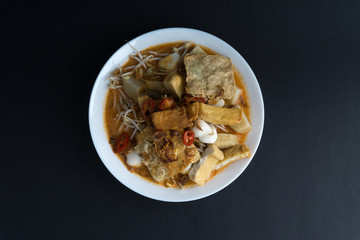 Curry noodles in a plate on dark background with selective focus and crop fragment