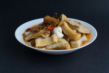 Curry noodles in a plate on dark background with selective focus and crop fragment