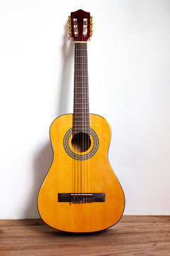 Classic guitar on wood floor with white wall. Favorite string music instrument.