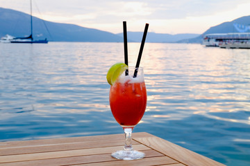 Cocktail glass with lemon on wood table  with seascape and skyline in the evening with sunset tone style   Sea wave background Background of stunning turquoise sea Travel concept
