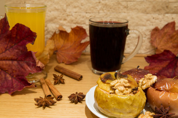 Mulled red wine with healthy dessert, baked apples with honey and nuts. Decorated with dried colorful leaves, cinnamon rolls and anise stars. Close up.