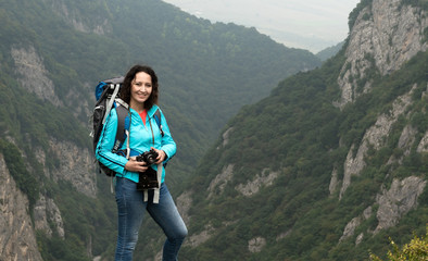 A woman tourist is going to shoot on a mountain landscape.