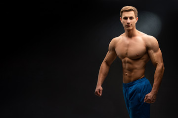 Fototapeta na wymiar Sports wallpaper on dark background. Power athletic guy bodybuilder. Sport nutrition banner.