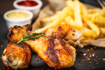 Grilled drumsticks with french fries and vegetables on wooden background