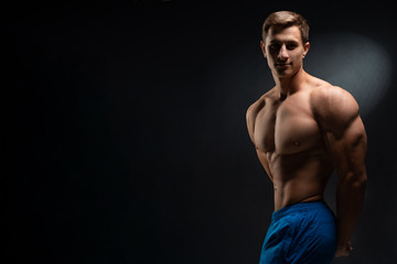 Fototapeta premium Sports wallpaper on dark background. Power athletic guy bodybuilder. Sport nutrition banner.