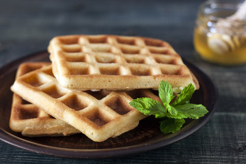 Viennese, Belgian waffles with honey on a white plate.